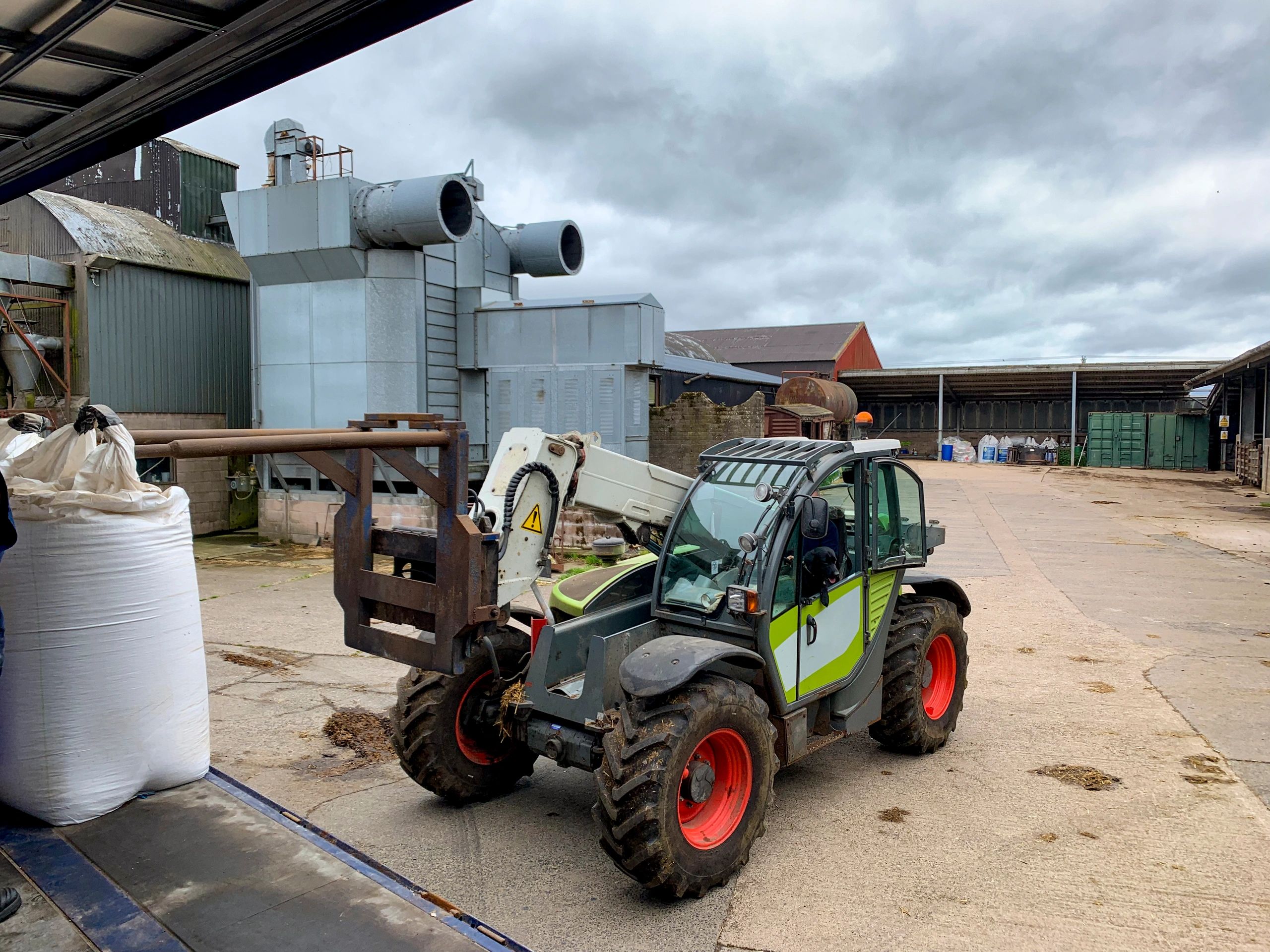 Farm telehandler parked near agricultural buildings
