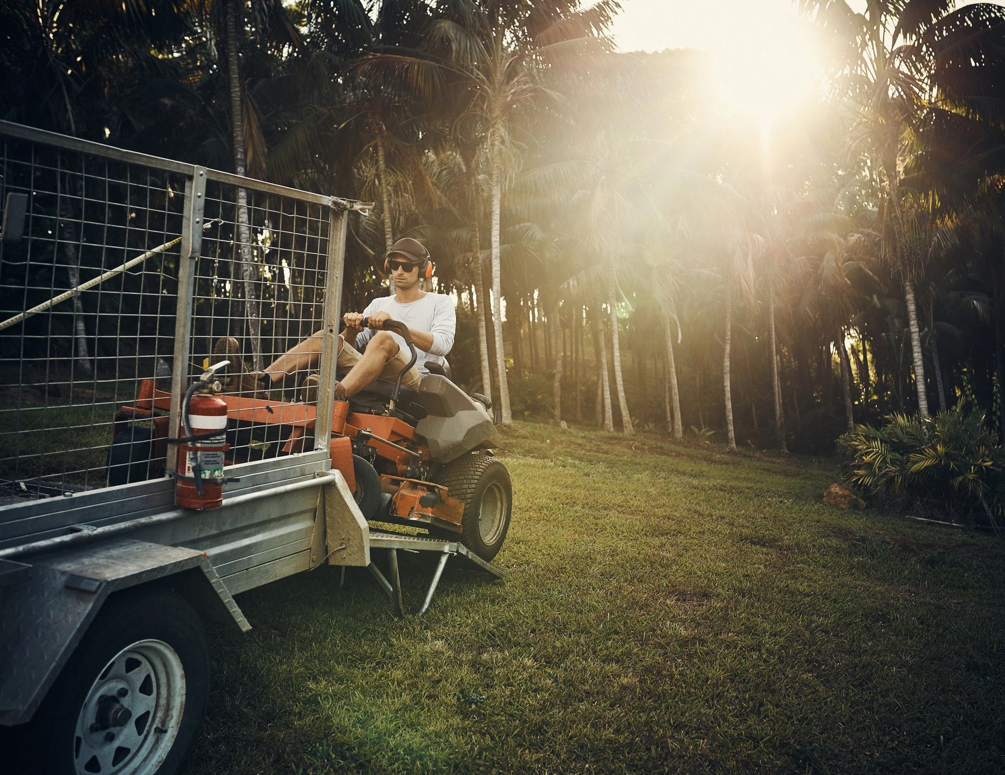 Landscaper unloading a riding mower from a trailer